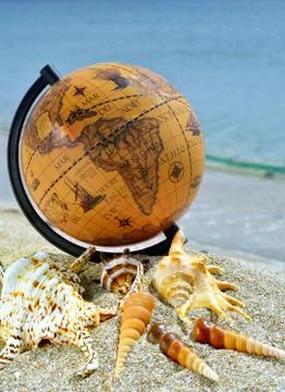 Globe with seashells on tropical beach. Stock Photos