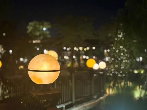 Globe-shaped lantern sitting atop a wooden post in an outdoor garden Stock-Fotos