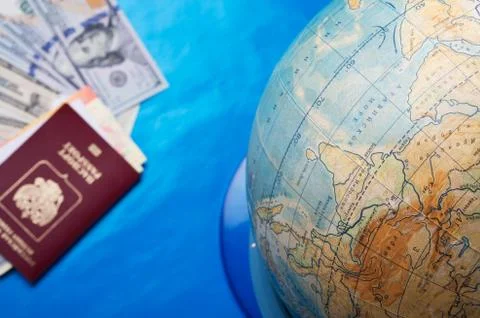 Globe sphere orb model effigy with passport, tickets and dollars around  blue Stock Photos