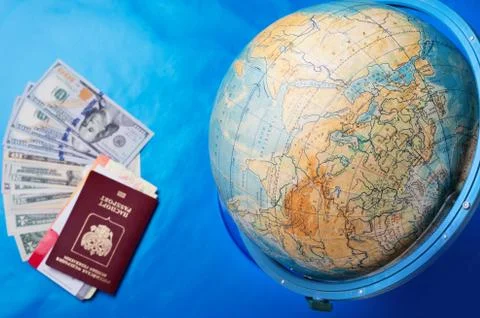 Globe sphere orb model effigy with passport, tickets and dollars around  blue Stock Photos