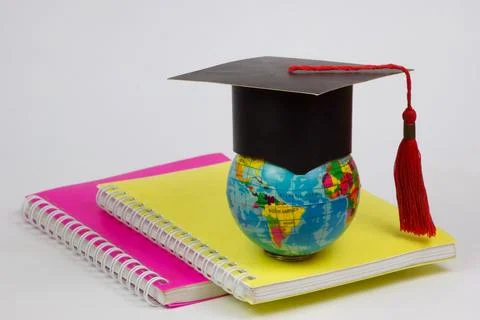 A globe in a students hat on a stack of notebooks for education Stock Photos