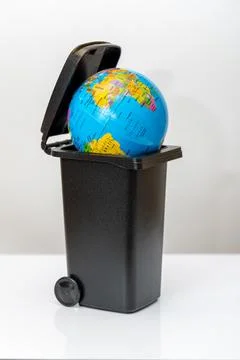 Globe in trash bin symbolizing discarded world and environmental neglect Stock Photos