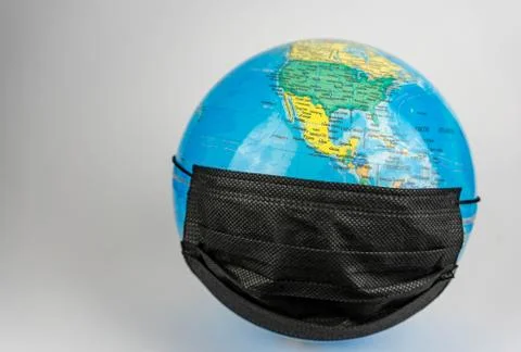 Globe while wearing mask symbolizing pandemic around the world. Planet earth  Stock Photos