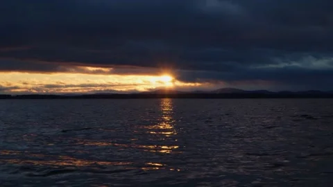 Gloomy cloudy sunset on the lake. Rays of bright sun and dark clouds. Stock Footage 255374865