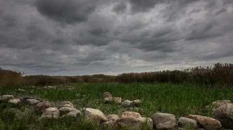 Gloomy dark clouds over the field and stones zoom-in Stock-Footage 64823191