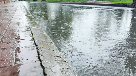 Gloomy Raindrops Splash into Deep Puddles Along a Lonely Suburban Street Stock Footage 334891986