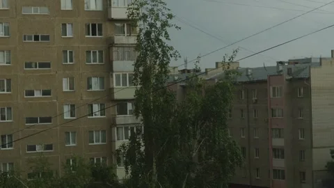 A gloomy sky over typical old panel residential buildings and green birch Stock Footage 336559523