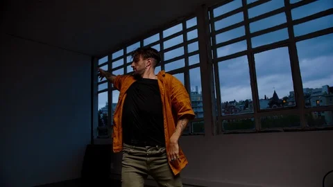 Gloomy tattooed guy dancing alone at dark leisure time in loft space with urban Video stock 109365702