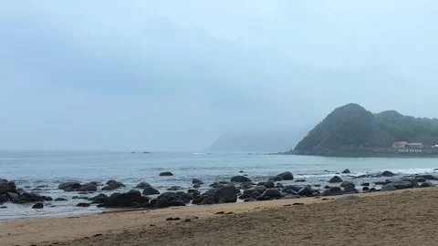 A gloomy view opens up over the sandy and rocky beach in Itoshima, Fukuoka. Stock Footage 335694376