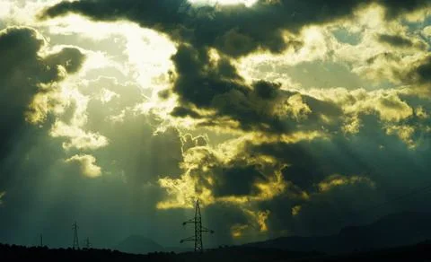 Glorious sunlight breaks through the storm clouds above the pylons. 스톡 사진