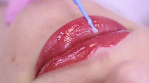Gloss on pink lips.  Macro shot of applying gloss on pink lips with a white back Stock Footage 131433411