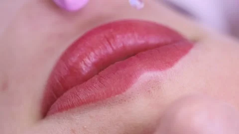Gloss on pink lips.  Macro shot of applying gloss on pink lips with a white back Stock Footage 131433644