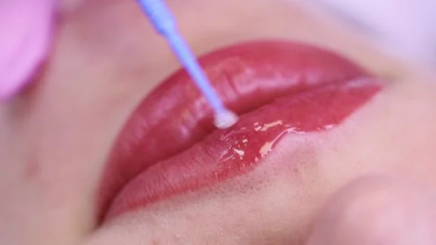 Gloss on pink lips.  Macro shot of applying gloss on pink lips with a white back Stock Footage 131433725