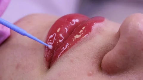Gloss on pink lips.  Macro shot of applying gloss on pink lips with a white back Stock Footage 131433939