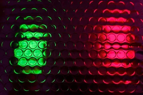 Glossy bubble wrap lit by green and red neon light creates an abstract textur Stock Photos