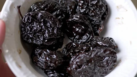 Glossy Dark Dried Prunes Resting Inside a White Ceramic Bowl Video stock 339069202