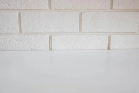 A glossy, empty table surface against a white brick wall Stock Photos