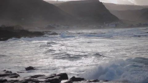 Glossy ocean waves in the sun with the mist near the mountains Stock Footage 128736064