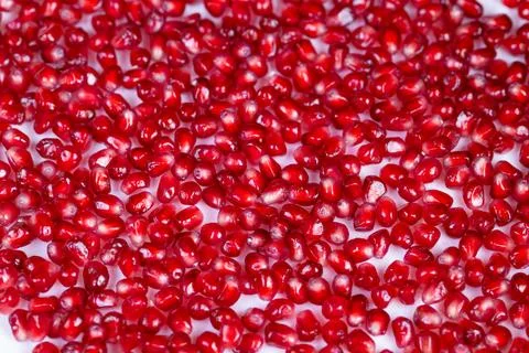 Glossy red arils on white. Bright pomegranate seeds with vibrant texture. D.. Stock Photos