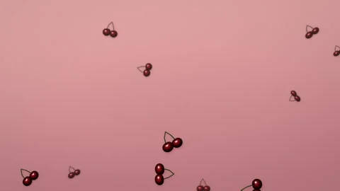 Glossy red cherry pairs falling on blush pink, summer fruit 4K seamless loop Видео 347991728