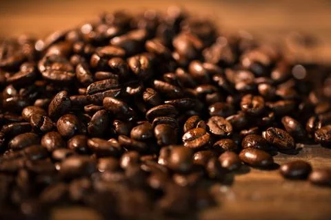 Glossy roasted coffee beans are glistening on warm wooden tabletop in flat Stock Illustration