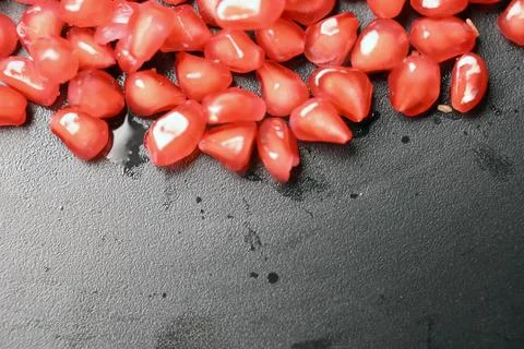 Glossy Ruby Pomegranate Seeds on Black Stone Background Stock Photos