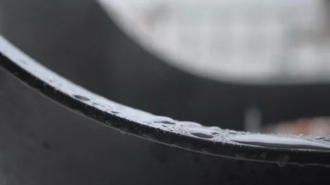 Glossy water drops sliding down curved black plastic chair Stock Footage 128540595