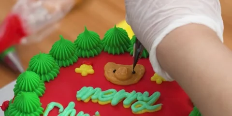Gloved Baker Decorating Christmas Cake with Merry Text and Frosting Stock Footage 343588518