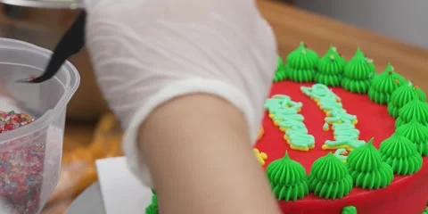 Gloved Baker Decorating Christmas Cake with Sprinkles and Green Frosting Stock Footage 343588570