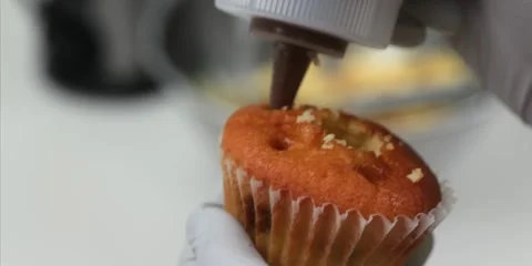 Gloved Baker Filling Fresh Cupcake With Chocolate Cream Stock Footage 343588642