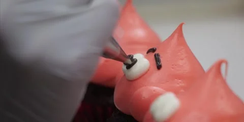 Gloved Baker Piping Cute Bear Face Details on Orange Cupcake Frosting Stock Footage 343588726
