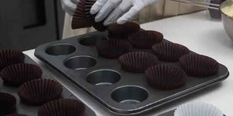 Gloved Baker Placing Chocolate Paper Liners Into Muffin Baking Pan 스톡 동영상 343588539
