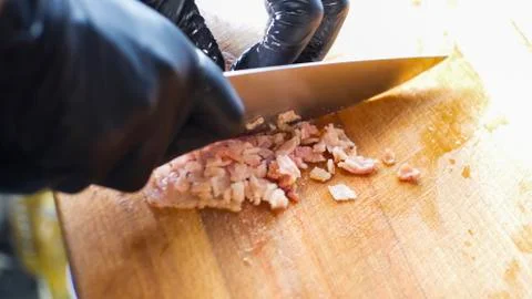 Gloved chef cuts meat Stock Photos