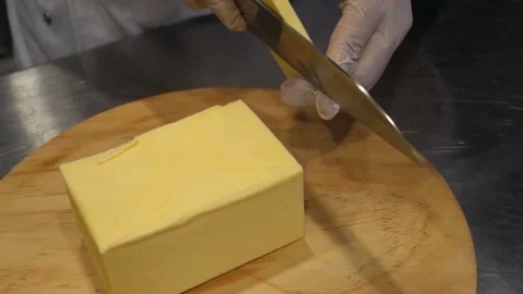 Gloved Chef Cutting Large Block of Fresh Butter on Wooden Board Stock-Footage 345291848