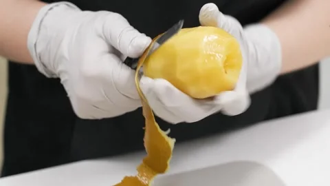 Gloved Chef Hands Peeling a Yellow Fruit for Dessert Preparation Stock Footage 343020471