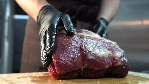 Gloved chef oiling a large raw piece of meat Stock Footage 144873459