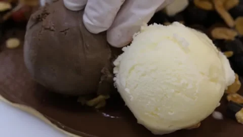 Gloved Chef Placing Fresh Scoops of Ice Cream onto a Chocolate Crepe Stock-Footage 345654713