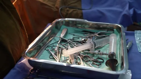 Gloved clinician selects tools from a sterile surgical tray with syringes and Stock Footage 328403269
