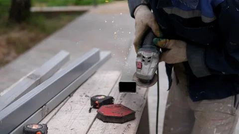 Gloved construction worker grinding metal tube outdoors, bright sparks flying Stock-Footage 344874409