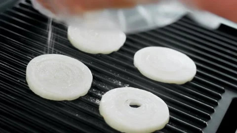 Gloved cook placing white onion slices onto grill plates, 4K Stock Footage 341119686