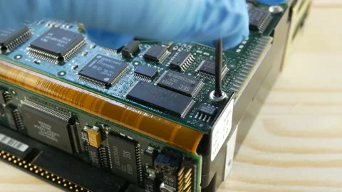 A gloved craftsman tightens a bolt in a computer hard drive with a screwdriver Stock Footage 166269595