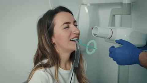A gloved dentist makes an X-ray of the teeth and shows it to the patient on a Stock Footage 150934437