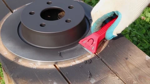 A gloved hand is brushing off excess paint from a painted car brake disc Vídeo Stock 144622578