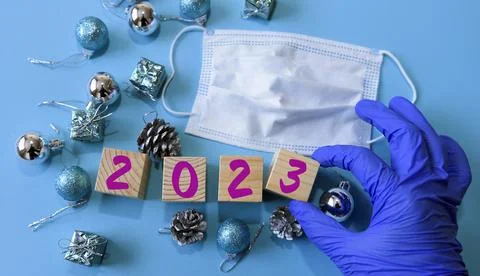 A gloved hand changes the year to 2023 with wooden cubes. Stock Photos