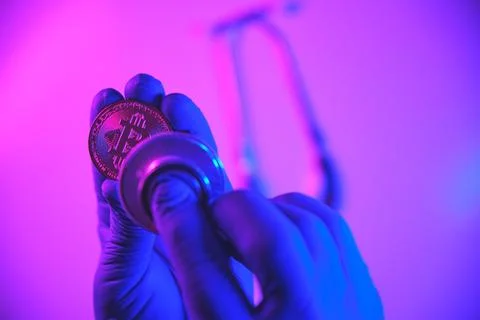 Gloved hand checking bitcoin financial health with stethoscope Stock Photos