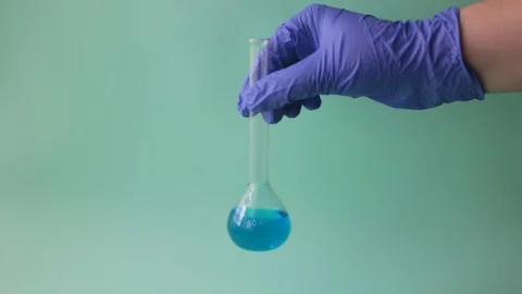 Gloved hand chemist mixing liquid from a test tube. Blue background. Stock Footage 128730510