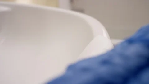 A gloved hand cleans a bathroom sink with disinfectant wipes Video stock 127225614