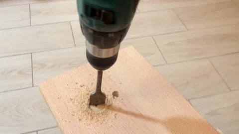 Gloved hand drilling a hole in a wooden plank with a cordless drill Stock Footage 328816632