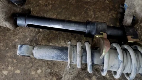 Gloved hand holding a car shock absorber with compressed spring Stock Footage 333701654