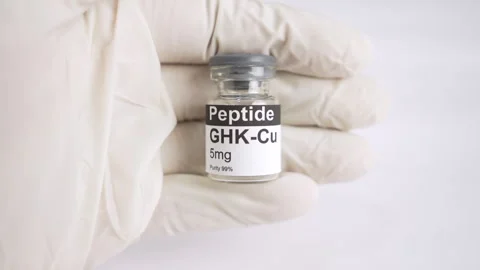 Gloved hand holding an GHK Cu peptide vial Видео 343617106